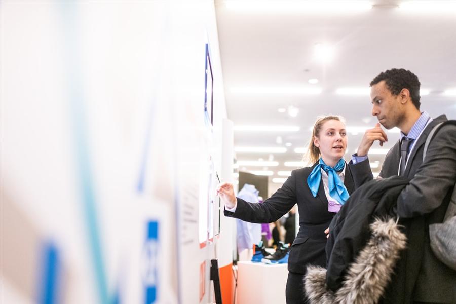 Event team member walking a visitor through a display at an exhibition stand