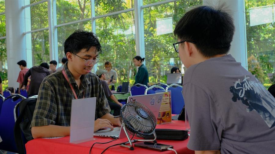 Recruiter and prospective student talking across a table at a busy fair